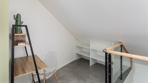 A modern, minimalist room with a wooden desk, a clear chair, and a cactus on a shelf. - Le Saint Martin 1 - Bel appartement moderne et confortable (Rennes)
