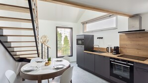 A modern kitchen with a dining area, featuring a staircase, built-in appliances, and a large window. - Le Saint Martin 1 - Bel appartement moderne et confortable (Rennes)