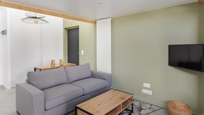 A modern living room with a grey sofa, wooden coffee table, and a mounted TV. - Le Saint Martin 1 - Bel appartement moderne et confortable (Rennes)