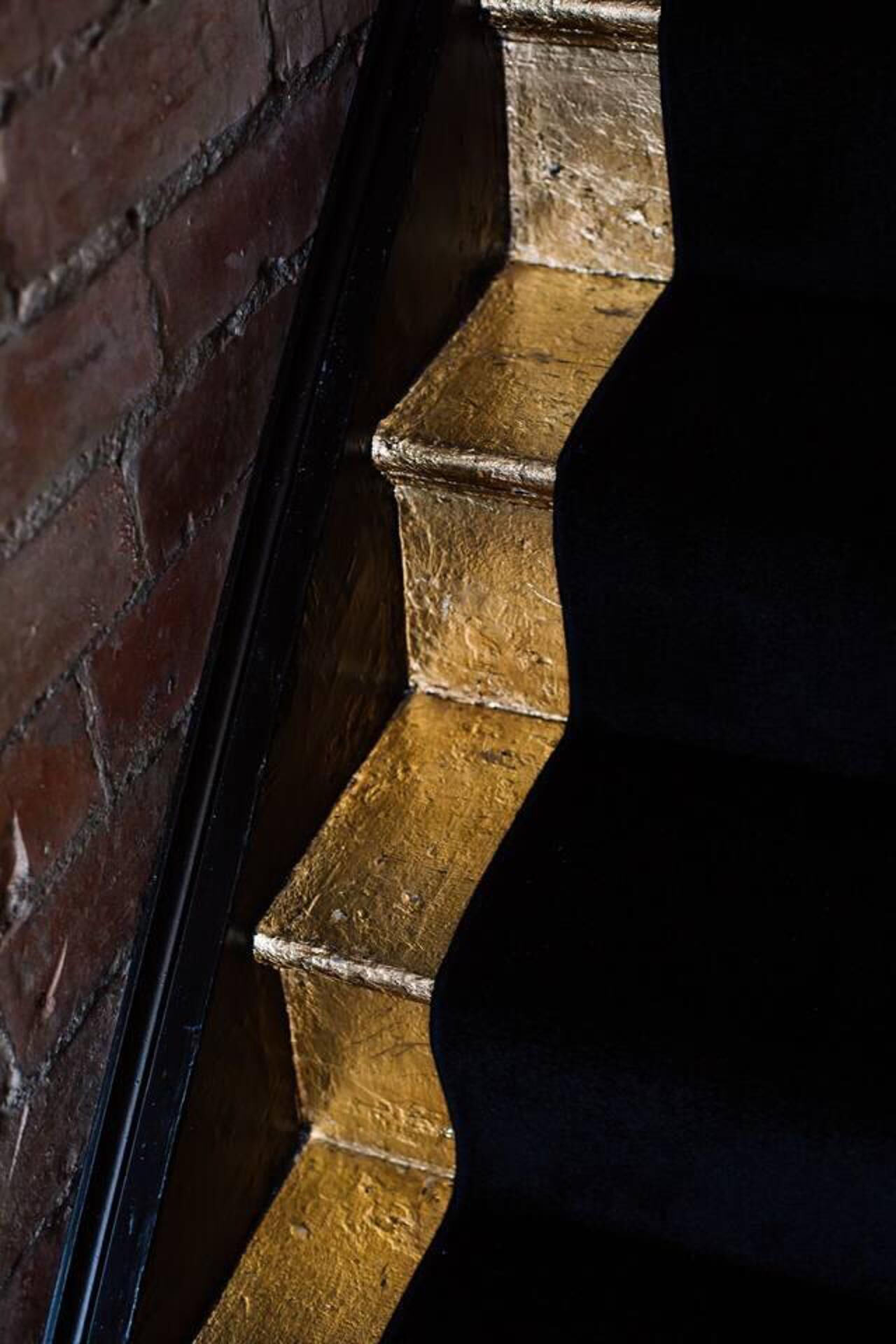 A staircase with a brick wall on one side and a dark-colored handrail on the other.