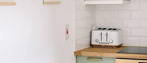 A kitchen with white cabinets, a toaster, a microwave, and a stove.