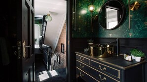 A modern bathroom with a black vanity, a round mirror, and green marble walls. - Luxury Designer 4-bed Home in the Heart of Belfast (Belfast)