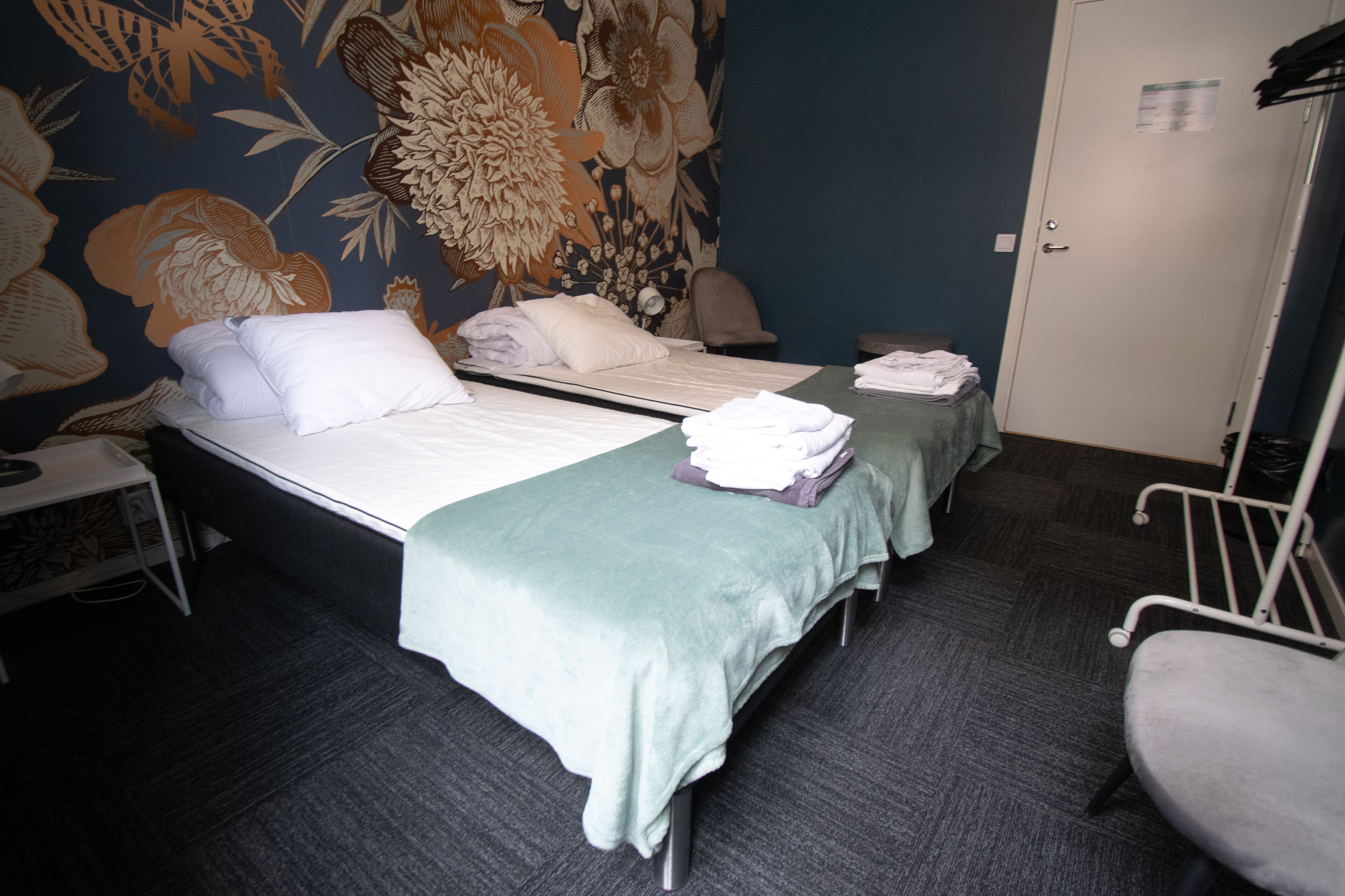 Una habitación de hotel con dos camas, un escritorio, una silla y una puerta.