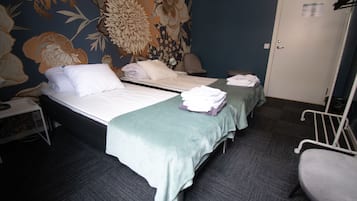 Een hotelkamer met twee bedden, een bureau, een stoel en een deur.