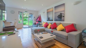A modern living room with a grey sofa, colorful cushions, a coffee table, and a painting on the wall.