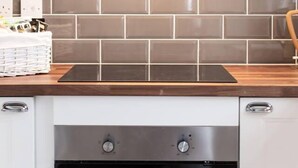 Une cuisine au design moderne, dotée d’un crédence en carreaux noirs, d’une hotte en acier inoxydable et d’un four encastré.