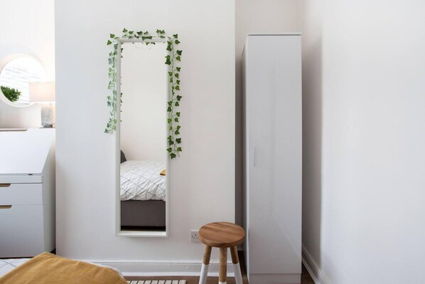 A bedroom with a bed, a wardrobe, a stool, and a mirror with ivy. - Luxurious 4-bedroom Home on Trendy Ormeau, Belfast (Belfast)