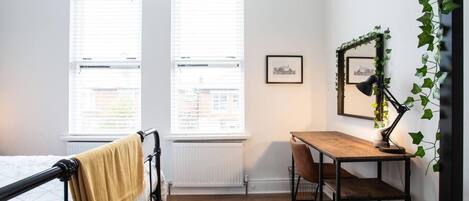 Een slaapkamer met een bed, een bureau en een radiator.