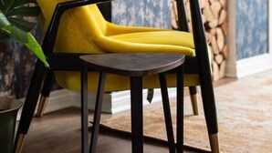 Un fauteuil jaune avec une structure noire et une petite table ronde placée devant.