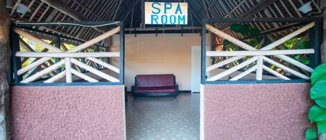 Entrada a un spa con un letrero, barandillas de madera, un banco acolchado y suelo de baldosas.