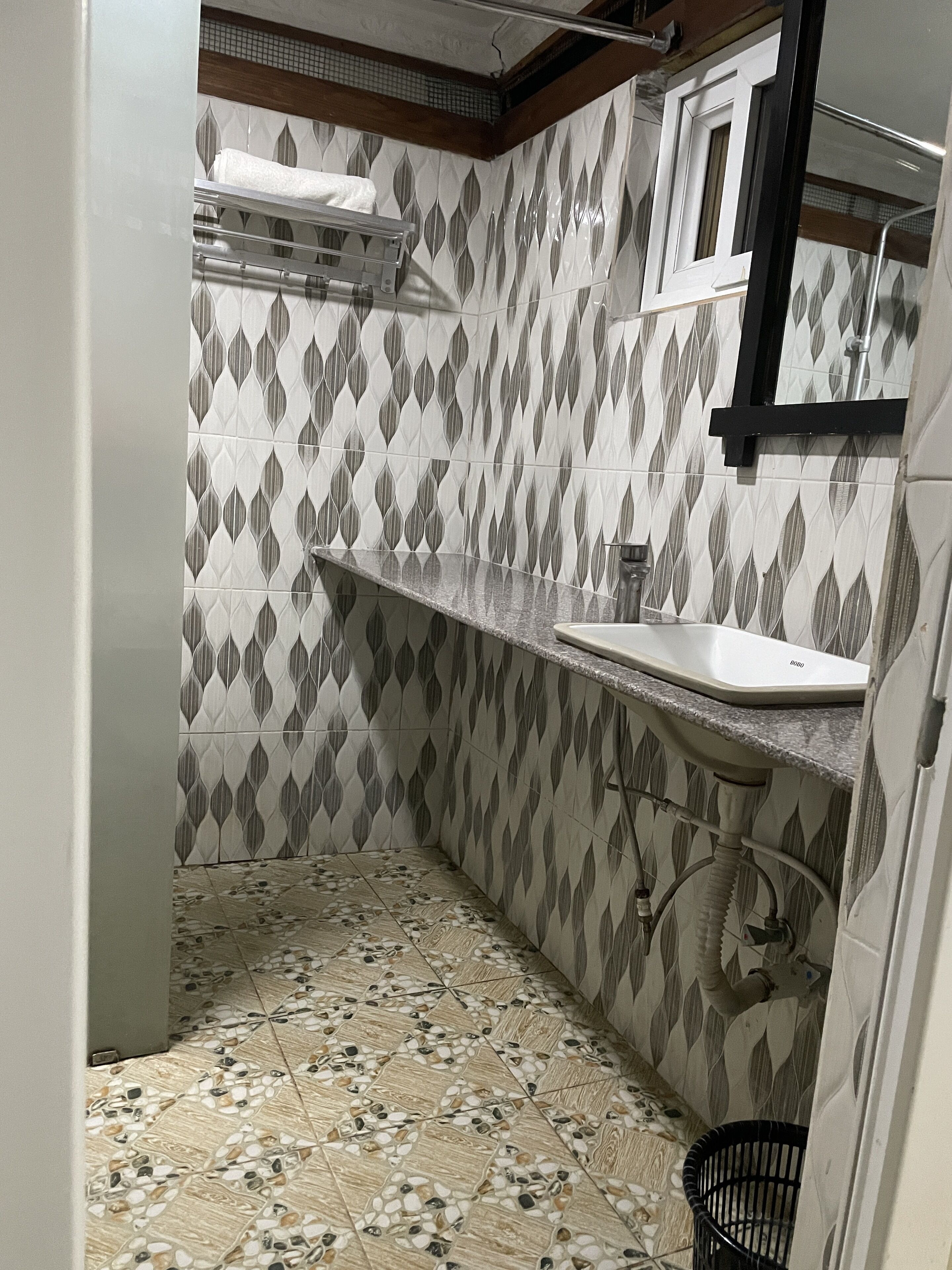 A bathroom with patterned tiles, a sink, and a shower area.