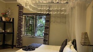 Un lit bien fait, recouvert d’une courtepointe blanche et agrémenté d’oreillers, une lampe de chevet et une fenêtre avec des rideaux.