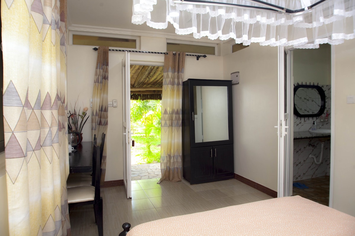 Une chambre à coucher avec un lit, une armoire et une salle de bain visible à travers une porte ouverte.