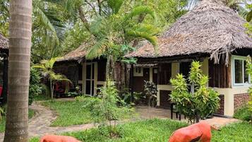 A tropical resort with thatched-roof cottages, lush greenery, and a pathway.
