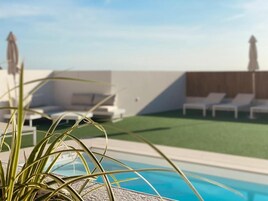 Una piscina al aire libre de temporada, sombrillas