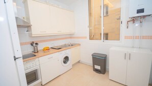 A compact kitchen with a washing machine, a sink, and a trash bin. - Rooms for rent in Barrio Chueca - Madrid INF1F (Madrid)