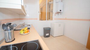 A kitchen with a sink, stove, and a window. There is a trash can and a small refrigerator. - Rooms for rent in Barrio Chueca - Madrid INF1F (Madrid)