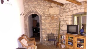 A rustic room with stone walls, a wooden TV stand, and a bookshelf.