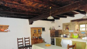 A rustic kitchen with wooden cabinets, a dining table with chairs, and a hanging light fixture.