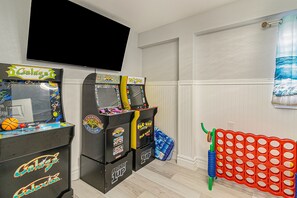 Una habitación con máquinas de videojuegos, televisión y mesa de billar.