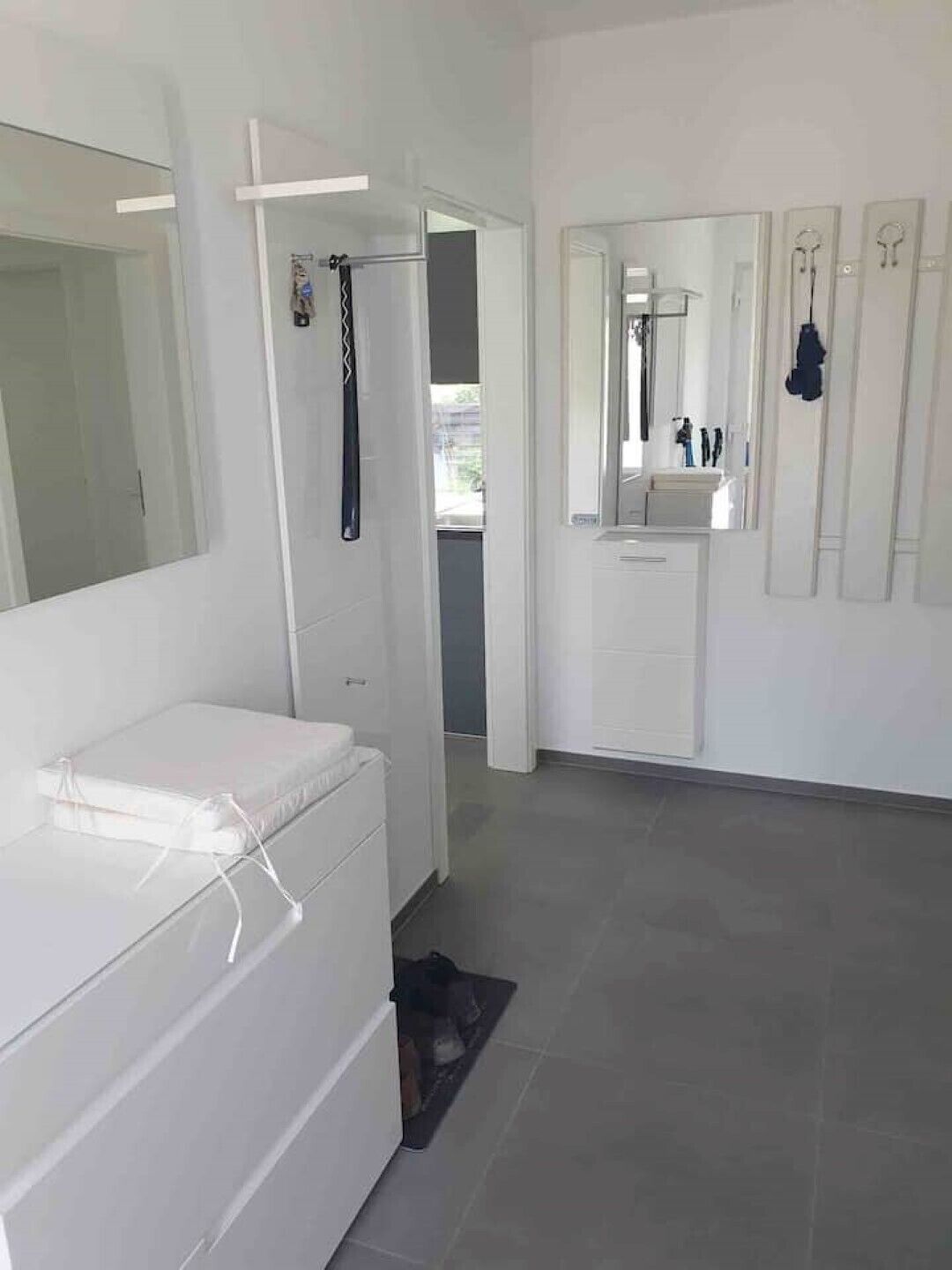 Een moderne badkamer met een witte wastafel, een spiegel en een douche.
