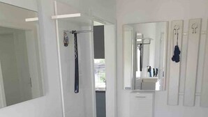 Ein modernes Badezimmer mit einem weißen Waschtisch, einem Spiegel und einer Duschkabine.
