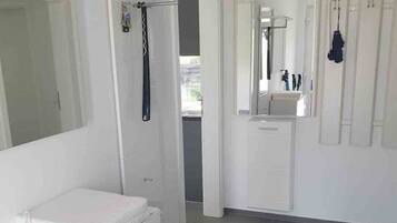 Een moderne badkamer met een witte wastafel, een spiegel en een douche.