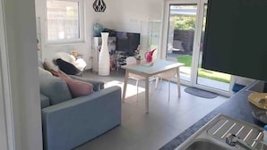 A modern living room with a sofa, a dining table, and a kitchen area with a sink and a TV. - Quiet apartment with terrace (Brechen)