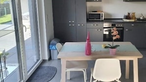A modern kitchen with dark cabinets, a microwave, and an oven. There is a dining table with two chairs and a pink vase. - Quiet apartment with terrace (Brechen)