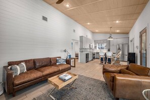 A spacious living area with a brown leather sofa, a coffee table, and a patterned rug. - Lakefront Estate: 2 Homes in 1 | Private Dock (Spicewood)