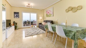 Un coin repas avec une table dressée pour quatre personnes, un canapé et une vue sur l’extérieur.