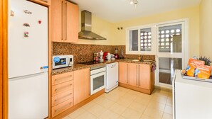 Une cuisine avec des meubles de rangement en bois, un four à micro-ondes, une cuisinière et un réfrigérateur.