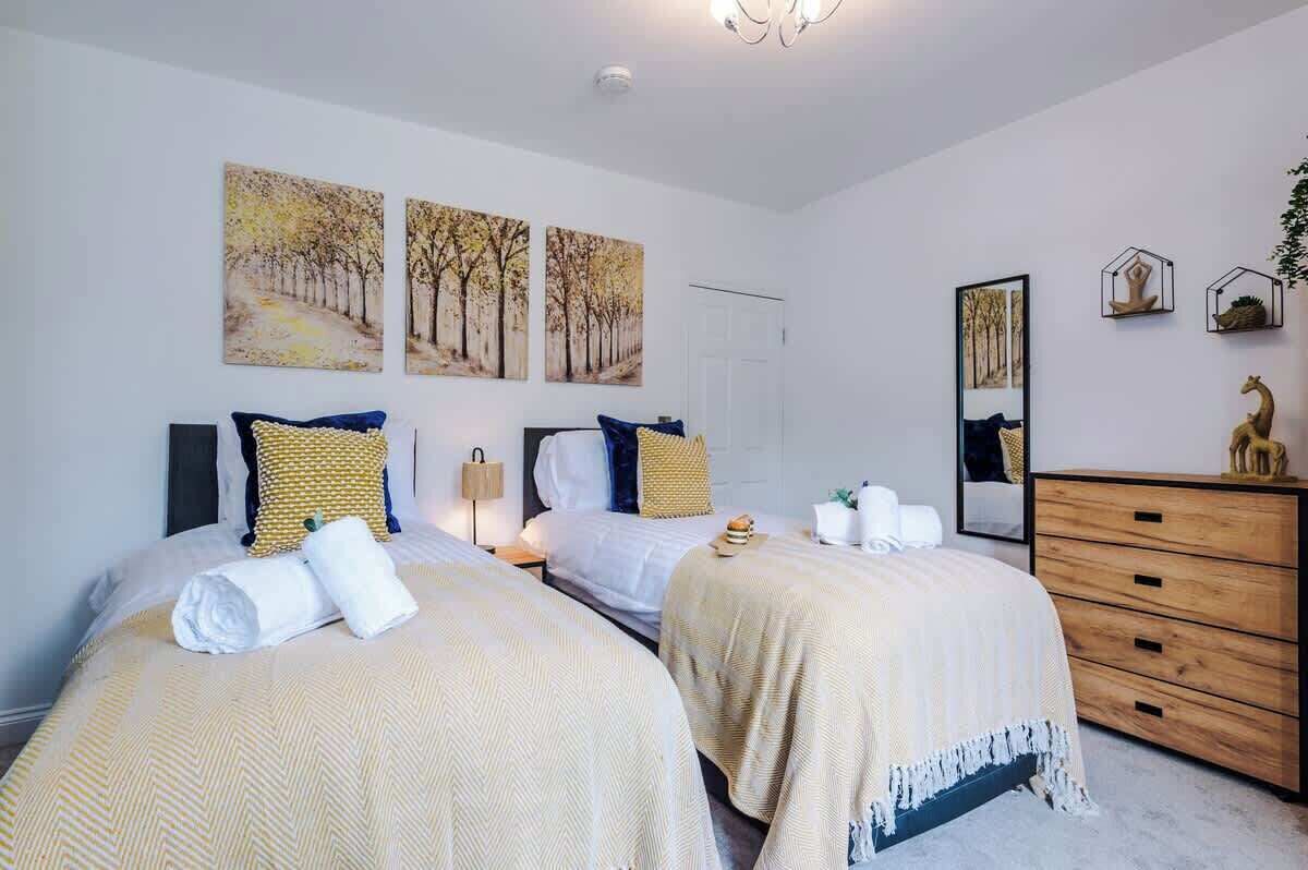Una habitación de hotel con dos camas, un aparador de madera y decoración en la pared.