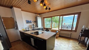 Eine moderne Küche mit einer zentralen Kochinsel, Holzböden und großen Fenstern mit Blick ins Freie.