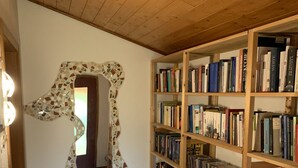 Ein Flur mit einer Holzbücherwand, voll mit Büchern und CDs, einer Mosaik-Wandkunst und einem gemusterten Teppich.