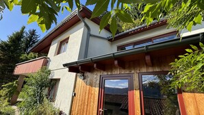 Ein zweistöckiges Haus mit Holzfassade, einem Balkon und einem Fenster.