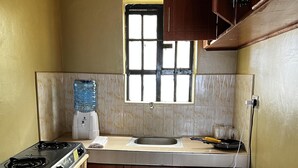 Une cuisine de taille réduite équipée d’une cuisinière à gaz, d’un évier et d’un réfrigérateur.