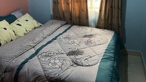 Une chambre à coucher avec un lit, des oreillers, des rideaux et une fenêtre.
