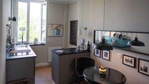 Een compacte keuken met een centraal eiland, een eethoek met een stoel, en een raam dat voor natuurlijk licht zorgt.