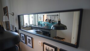 Een moderne keuken met een grote spiegel, afbeeldingen in lijsten en een hangende kruidenrek.