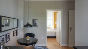 Een moderne kamer met een ronde eettafel, een zwarte hanglamp en ingelijste foto’s aan de wand.