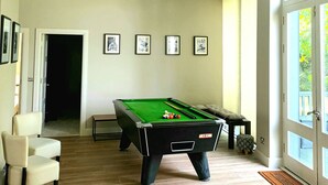 A spacious room with a pool table, a chair, and a door leading to another area. - Beautiful 2-bed Apartment Near Waterford City (Waterford)