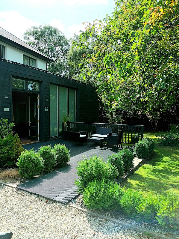 A modern house with a patio area featuring outdoor furniture and a well-maintained garden.