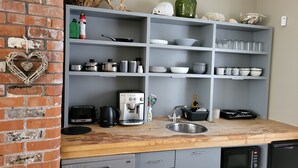 A kitchen with grey cabinets, a wooden countertop, a coffee machine, a kettle, a toaster, and a microwave. - Beautiful 2-bed Apartment Near Waterford City (Waterford)