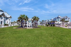 A well-maintained grassy area with palm trees and a white fence.