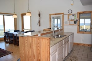 A kitchen with a wooden island, a sink, and a window overlooking a balcony. - Prospect Point- 4BR Waterfront | Screened Porch | Private Pier (Chincoteague)