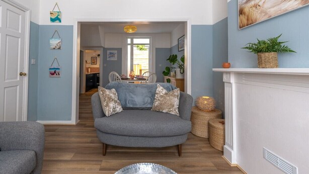A living room with a grey sofa, wooden flooring, and a white fireplace.
