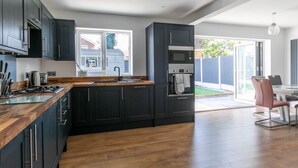 Eine moderne Küche mit dunklen Schränken, einer Holz Arbeitsplatte und einem Einbauofen.