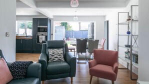 Ein modernes Wohnzimmer mit zwei Ledersesseln, einem Essbereich mit Tisch und Stühlen und einer Küche im Hintergrund.