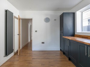 A modern kitchen with dark cabinets, a wooden countertop, and a window.